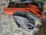 un appareil orange muni d'un cordon, posé par terre à côté d'un tissu