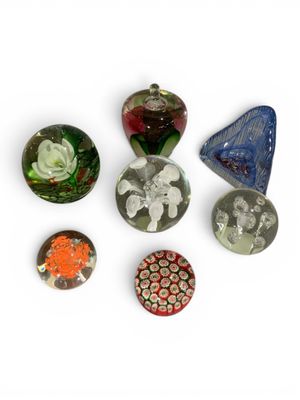 Plusieurs morceaux de verre de différentes couleurs sont disposés sur une surface blanche.