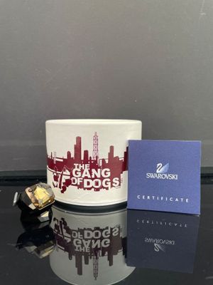 une tasse blanche ornée d'un motif rouge et blanc, à côté d'une boîte bleue