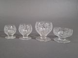 quatre verres à pied en verre transparent posés les uns à côté des autres sur une table