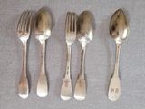 trois cuillères en argent et une fourchette sont alignées sur une table