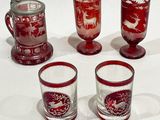 four red glass cups and a mug with a deer design on them