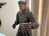 a statue of a man holding a book next to a statue of a sheep