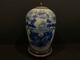 un vase bleu et blanc posé sur un socle, sur une table