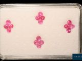 quatre diamants roses sont disposés dans un plateau posé sur une surface noire