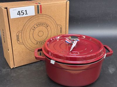 une cocotte rouge posée à côté d'un carton