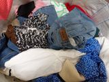 a pile of clothes that is sitting on a bed