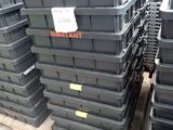 de nombreux conteneurs en plastique noir empilés sur des palettes dans un entrepôt