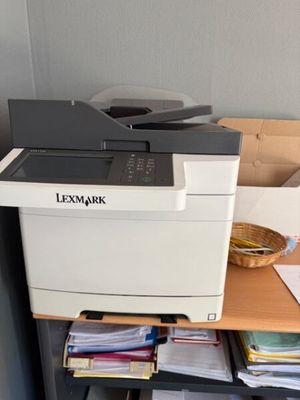 a printer sitting on top of a desk next to a pile of papers
