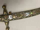 a gold dagger with a green stone on it
