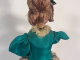 an image of a doll in a green dress on a blue surface