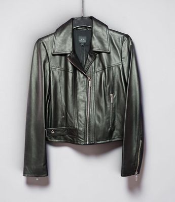 une veste en cuir noir suspendue à un cintre devant un mur blanc