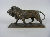 statue d'un lion posée sur un socle en bois, sur fond blanc