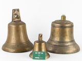 three brass bells on a white background with a green tag