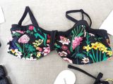 a black bra top with flowers on it next to a pair of shoes