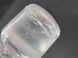 a close up of a bottle of water with a cell phone in the background