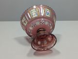 a pink vase with a gold rim sitting on a table