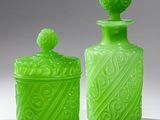 two green glass jars sitting next to each other on a white surface