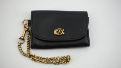 un sac à main noir auquel est suspendue une chaîne dorée sur le côté