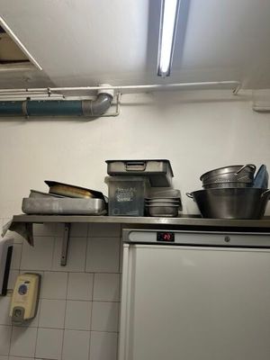 un réfrigérateur blanc dans une cuisine, sur lequel sont posés de nombreux plats et casseroles