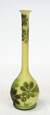 a green vase with leaves on it on a white surface