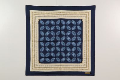 un foulard carré à motifs cachemire bleus et blancs accroché à un mur blanc