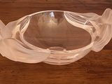 un saladier en verre posé sur une table en bois, avec une source de lumière en arrière-plan
