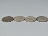 four different coins sitting on top of each other on a white surface