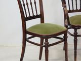 two wooden chairs with green upholstered cushions sit side by side