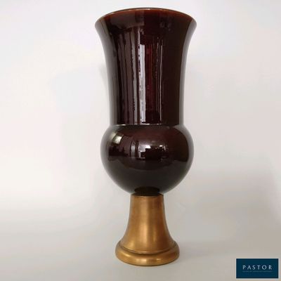 un vase marron avec un socle doré sur fond blanc
