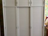 a white cabinet with shutters in the corner of a room