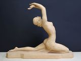 statue d'une femme dans une posture de yoga, posée sur un socle en bois