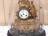 une horloge en or sous un dôme de verre sur une table