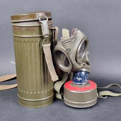 a gas mask next to a canister on a table