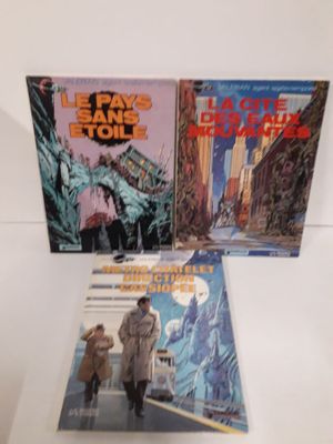 trois livres posés sur une table, avec un homme qui passe devant