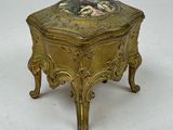 a small gold box with a floral design on it