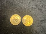two gold coins sitting next to each other on a black surface