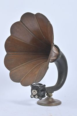 un vieux gramophone posé sur un support, sur fond blanc