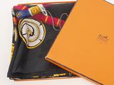 an orange box with a watch and a scarf inside of it