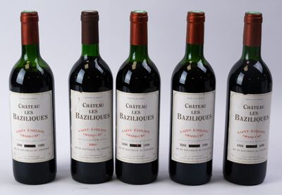 quatre bouteilles de vin rouge sont alignées sur une surface blanche