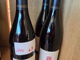 three bottles of red wine sit on a shelf in a wine cellar