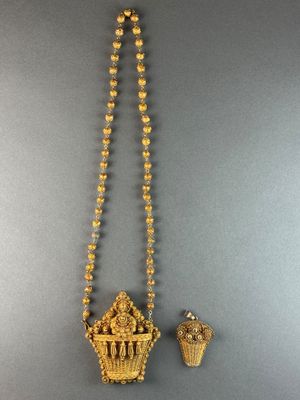 a gold necklace with a cupcake pendant and a pair of earrings