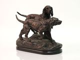 statue représentant deux chiens debout sur un rocher, posée sur un socle blanc