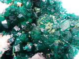close up of a cluster of green crystals on a white surface