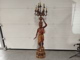 a statue of a man holding a chandelier in a garage