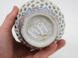 a person holding a white and blue vase with tags on it