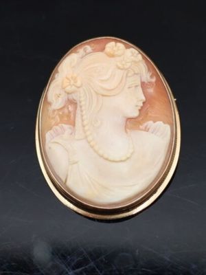un gros plan sur une broche représentant une femme en robe