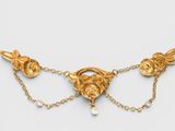 a close up of a gold necklace with pearls on a chain