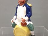 une figurine représentant un homme assis sur un tonneau