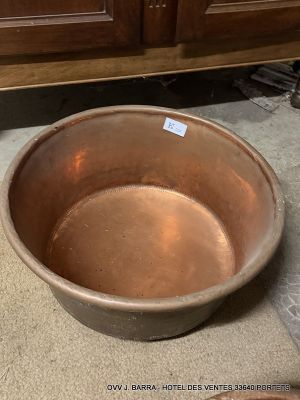 a large metal bowl sitting on the floor next to a wooden cabinet